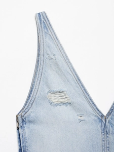 Detailaufnahme von hellblauem Jeansstoff mit Used-Look, Löchern und silbernem Reißverschluss