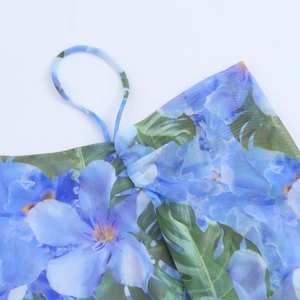 Close-up of thin shoulder straps and floral blue mesh fabric on summer dress