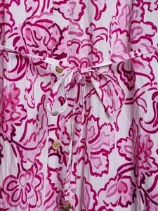 Detailed macro view of pink floral print on white fabric with wooden buttons and waist tie