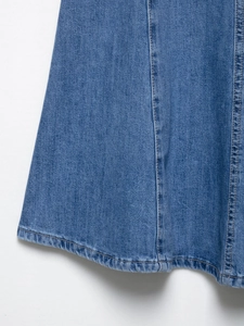 Detailed macro view of denim dress hem with classic yellow topstitching and blue fabric texture