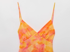 Detail shot of the V-neck spaghetti strap design with vibrant orange abstract floral print
