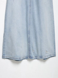 Detail eines hellblauen Jeansrock-Saums mit modischen Distressed-Löchern und Ziernähten
