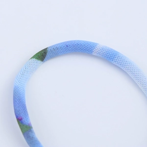 Macro detail of elastic knitted fabric with green and purple floral pattern and texture