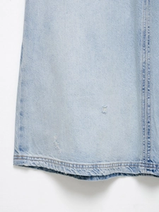 Detail eines hellblauen Jeanskleides mit Distressed-Rissen und gewaschener Baumwolle