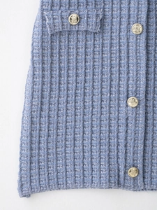 Détail du tissu en tweed bleu clair avec quatre boutons dorés gravés de style blason
