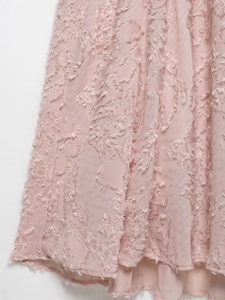 Detailed close-up of pink halter dress fabric with 3D floral jacquard and tassel texture