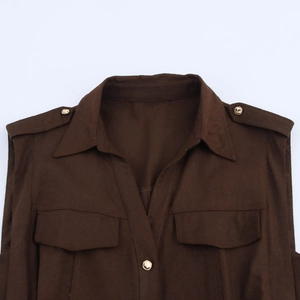 Detail of dark brown pleated dress featuring shoulder epaulets and gold metal buttons