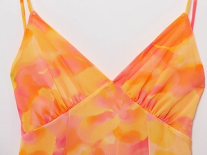 Detail of V-neck strap dress showing orange tie-dye print on breathable mesh fabric
