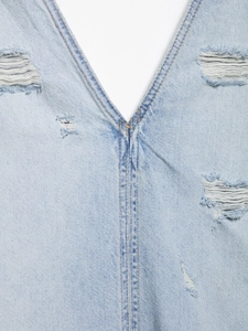 Detailansicht aus hellem Denim-Stoff mit modischen Rissen und Vintage-Wascheffekt