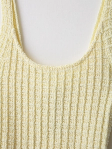 Close-up of elegant pale yellow knit tank top showing waffle texture and U-neck stitching