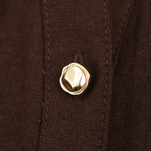 Macro detail of high-quality brown fabric texture and a golden irregular metal button
