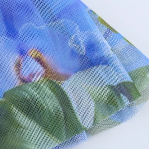Macro detail of breathable blue and green floral mesh fabric with a fine net texture