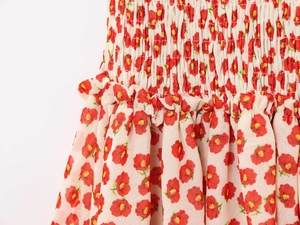 Close-up of smocked waist with red floral print and ruffle details on summer dress