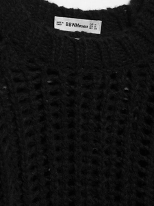 Gros plan sur la texture du tricot et l'étiquette de taille d'un haut noir à manches courtes