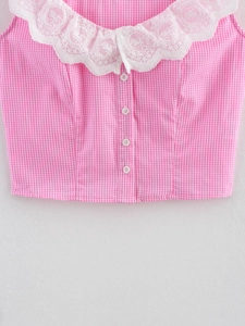 Detail of pink gingham vest featuring a white lace collar and decorative embroidery