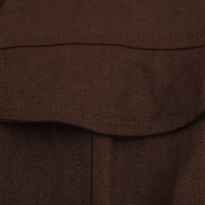 Detail of dark brown fabric texture and neat stitching on a buttoned pleated dress