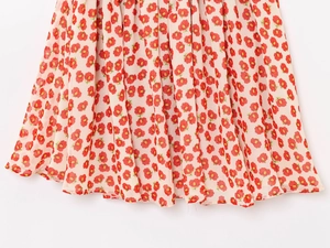 Detailed view of cream-colored pleated floral chiffon fabric with red flower pattern