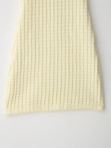 Macro view of creamy yellow knit fabric texture featuring a vertical waffle weave pattern