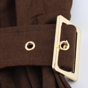 Macro shot of brown linen belt with a polished gold metal buckle and reinforced eyelets