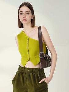 Dettaglio del gilet monospalla verde erba con bottoni e pantaloni casual verde oliva