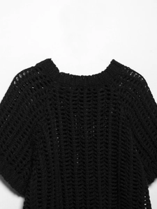 Détail de haut en crochet noir montrant la texture ajourée en V et l'encolure ronde soignée