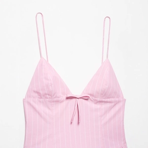 Pink and white vertical striped sundress featuring a deep V-neck and a cute bow detail