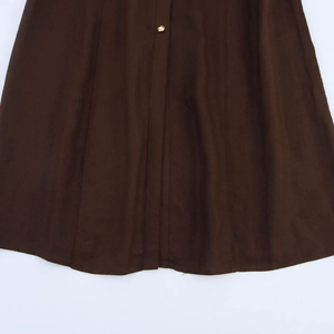 Detail view of dark brown pleated dress with golden button and vertical seam stitching