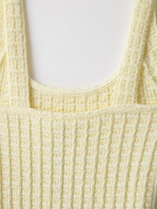 Detail of light yellow knit fabric featuring a waffle texture and square neckline