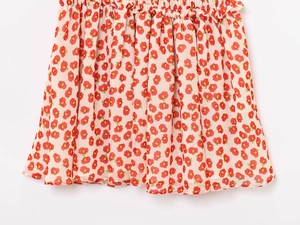 Detail of red floral print on beige chiffon fabric with pleated waist and A-line hem