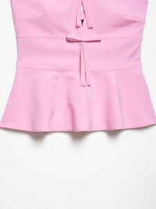 Detailed close-up of pink strapless top showing bow tie waist and peplum hem texture