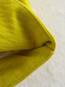 Dettaglio macro del tessuto giallo brillante con cuciture a doppio punto precise