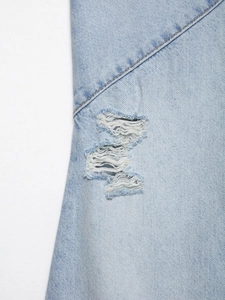 Detail aus hellblauem Denim mit Distressed-Rissen und feinen weißen Baumwollfasern
