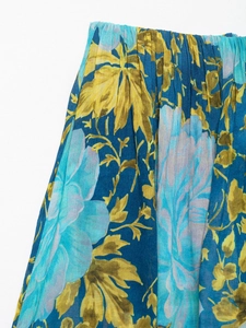 Detail of navy blue pleated dress with vintage yellow flower patterns and accordion folds