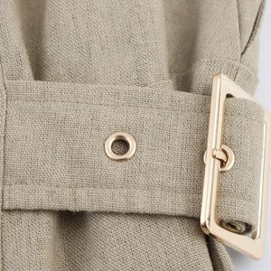Detail of khaki linen dress featuring a waist belt with gold buckle and metal eyelets