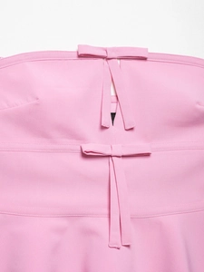 Detailed view of pink tube top featuring bow accents and cutout design in woven fabric