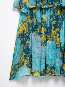 Close-up of blue floral print dress featuring pleated fabric and raw edge hem detail