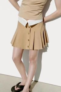 Détail de la jupe-short plissée kaki avec taille contrastée blanche et boutons ambrés