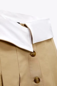 Vue détaillée de la minijupe kaki avec taille haute blanche pliée et boutons ambre