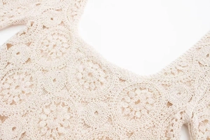 Detaillierte Makroansicht des beigen Häkelblumenmusters und der feinen Stricktextur