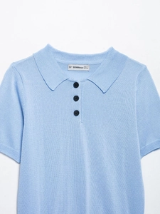 Détail du col d'un polo en maille bleu clair avec boutons et texture de tissu fine