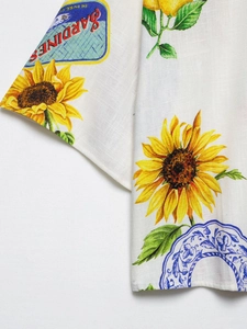 Vue détaillée du tissu en lin avec des motifs de tournesols et des étiquettes de sardines