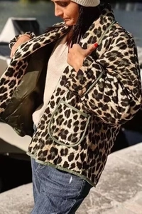Detailed view of women's leopard print quilted jacket with green trim and square pockets