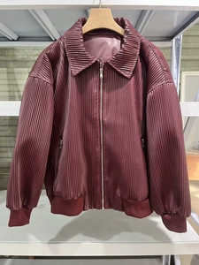 Detailed macro view of burgundy pleated bomber jacket with metallic sheen and zip pockets