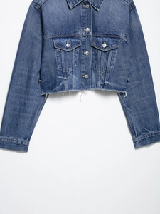 Detail view of cropped denim jacket with frayed hem and silver buttons on white background