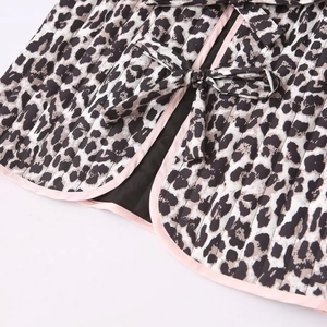 Dettaglio gilet trapuntato leopardato con bordi in raso rosa e chiusura con fiocchi