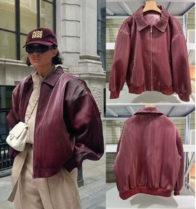 Detailed close-up of dark red pleated bomber jacket with ribbed cuffs and stand collar