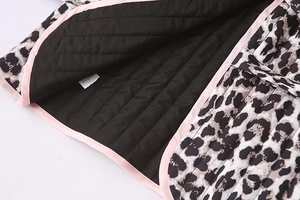 Dettaglio macro del gilet leopardato con bordi rosa e fodera interna trapuntata nera