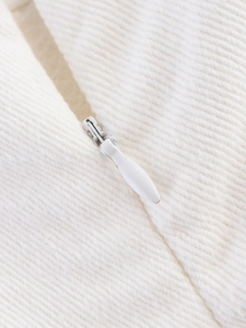 Close-up of a white pleated top featuring a smooth hidden zipper and twill fabric texture