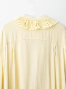 Dettaglio del collo a pieghe su una camicetta di chiffon giallo chiaro da donna