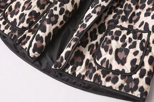 Detailed close-up of leopard print quilted jacket showing texture and black edge piping